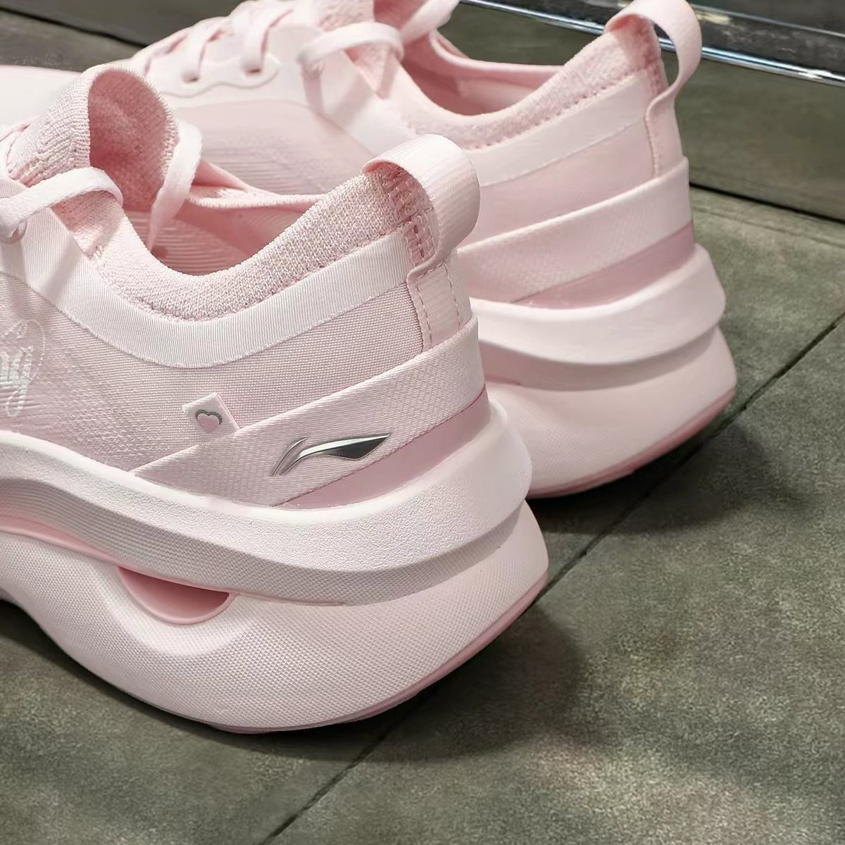 Light pink women's athletic sneakers with thick soles on a grey stone floor
