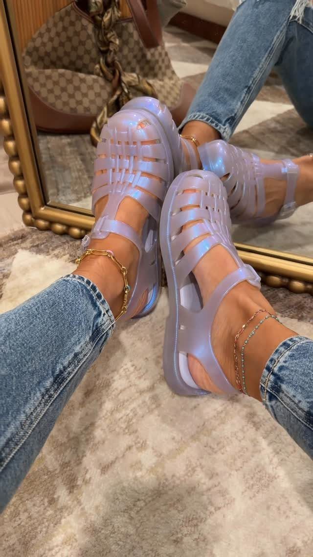 Iridescent purple jelly sandals with platform soles worn with blue jeans and gold jewelry.