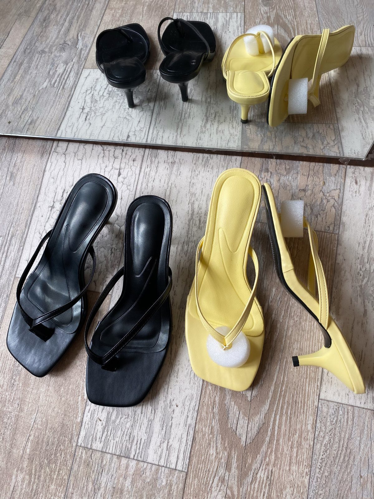 Black and yellow kitten heel sandals with thin straps on a wooden floor.