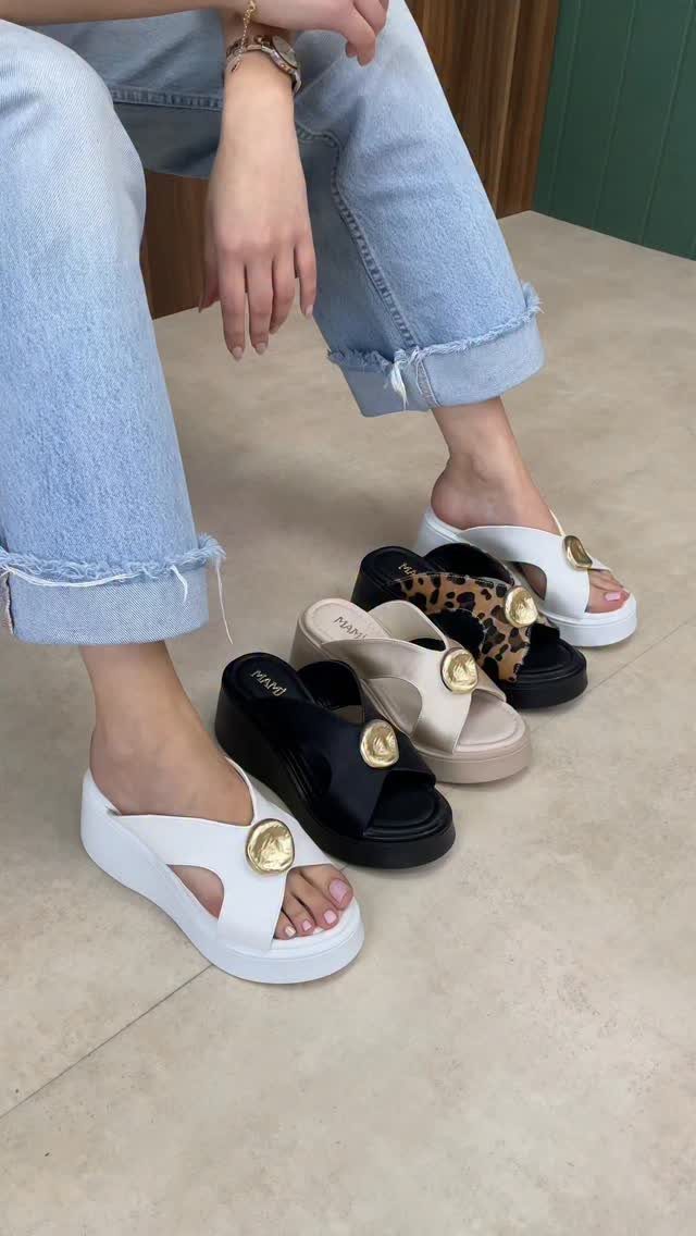 White wedge sandals on feet and several other colored wedge sandals on floor