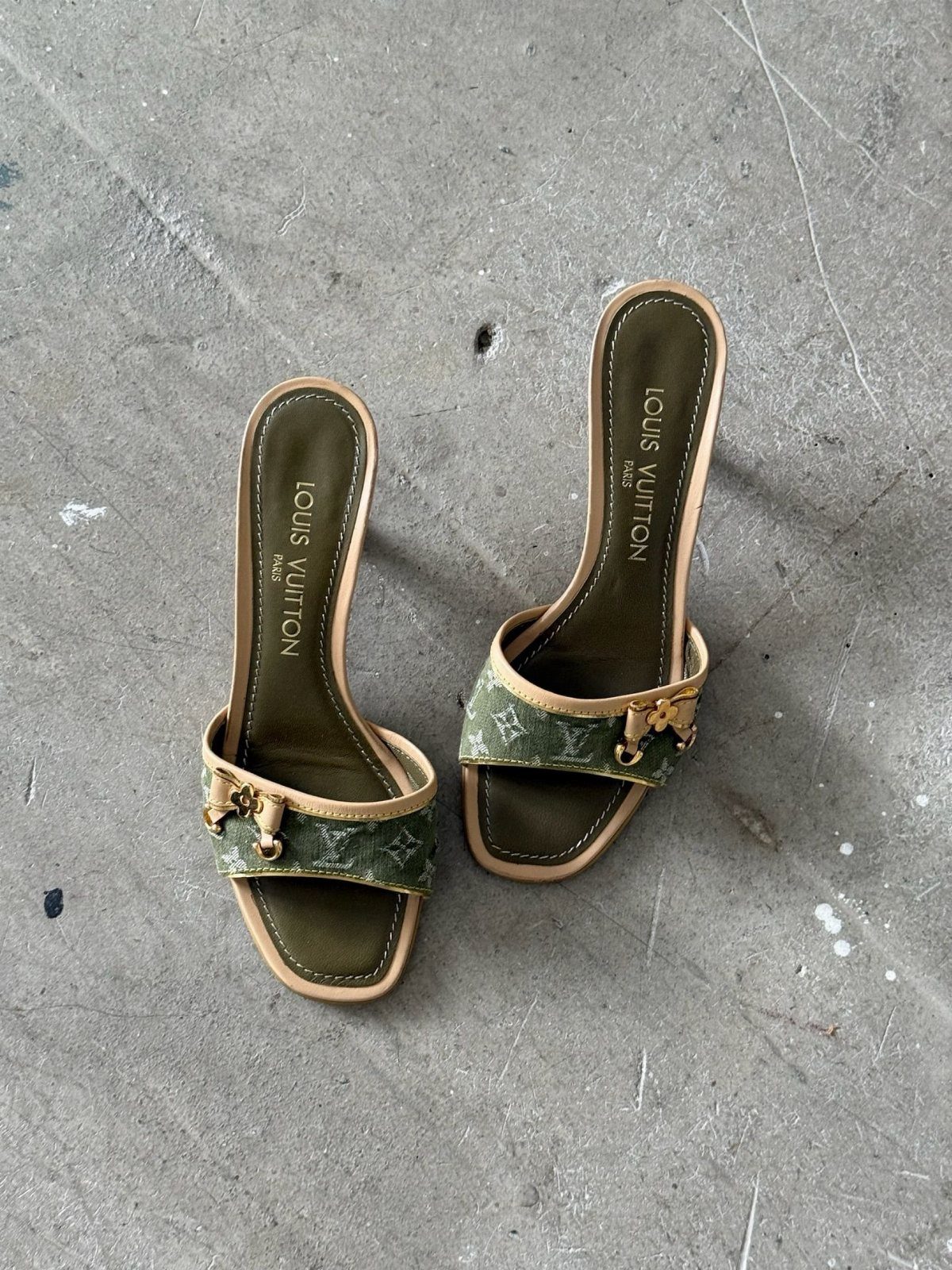 Louis Vuitton denim mule heels with monogram straps on a grey concrete surface