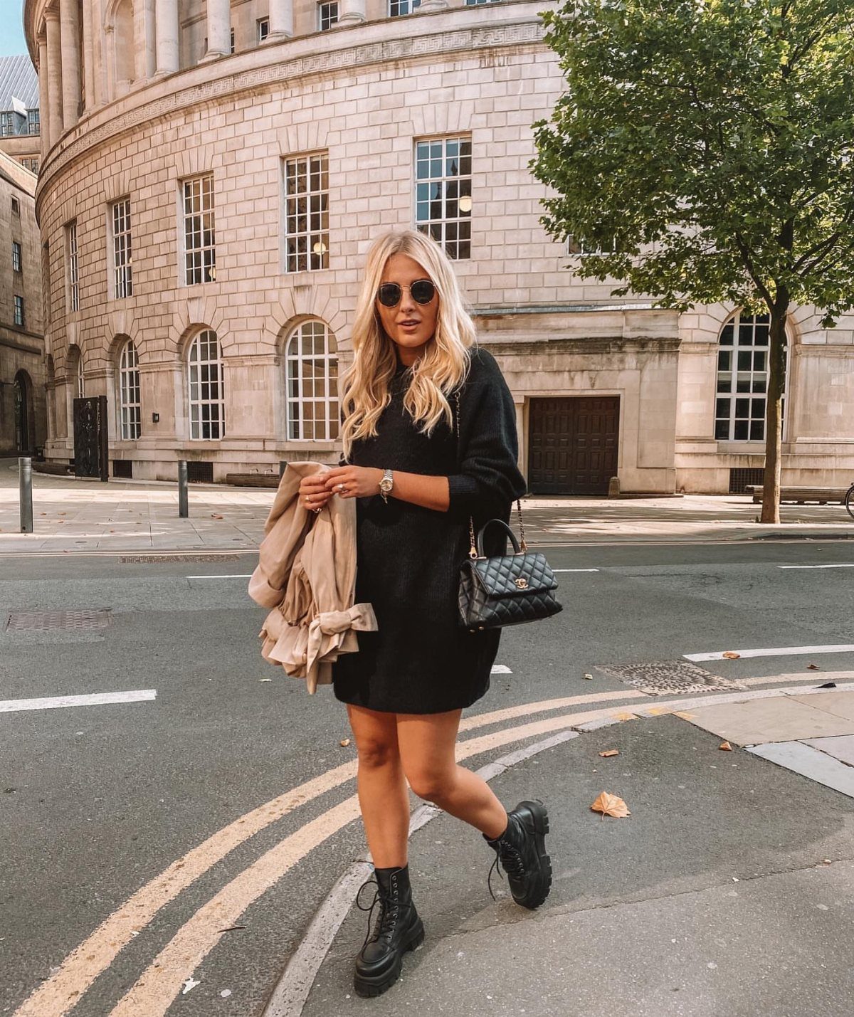 Woman in short black knit dress and chunky sole black boots on city street