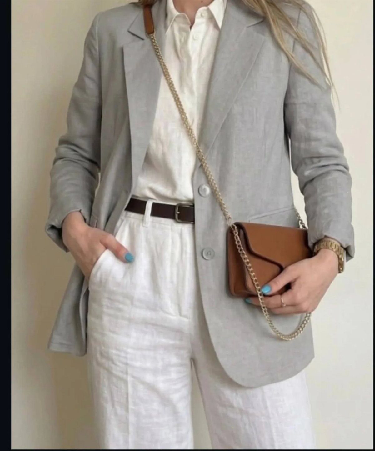 Woman wearing a light grey linen blazer, white shirt, and white trousers.