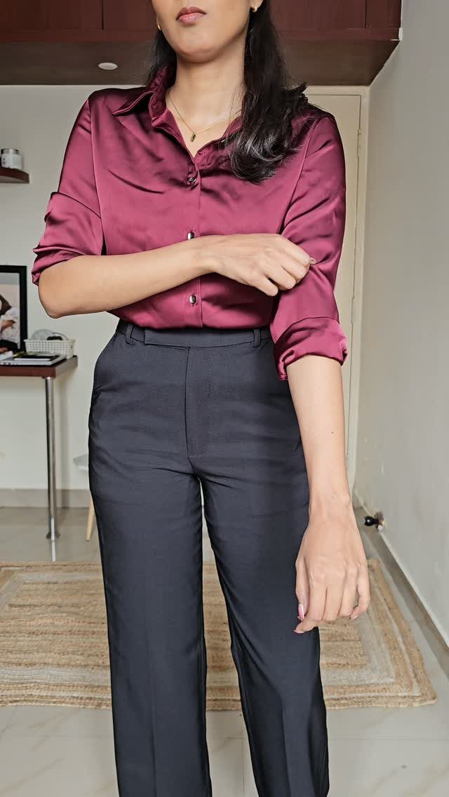 Woman wearing a magenta satin shirt and professional black high-waisted trousers.